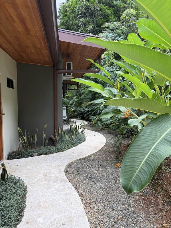 Un sendero curvo que conduce a un edificio con techo de madera y pared gris.