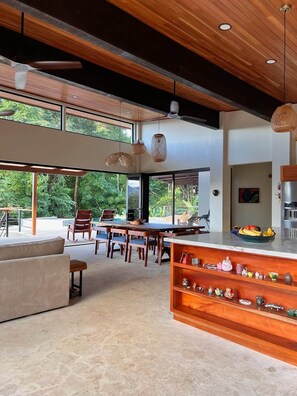 Amplia sala de estar con mesa de comedor, sillas, sofá y encimera de cocina decorada.