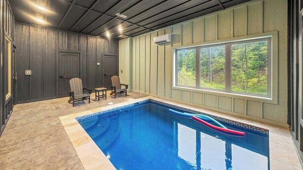 Une piscine intérieure donnant sur une forêt grâce à une grande baie vitrée.