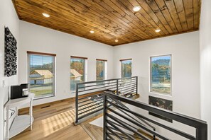 Ein modernes Interieur mit Holzboden, großen Fenstern und einer Treppe mit Metallgeländer.