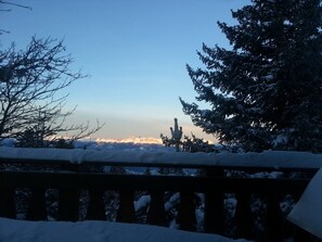 A snow-covered landscape with a wooden railing in the foreground and a clear sky in the background.