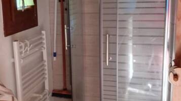 A bathroom with a glass shower enclosure, a toilet, and a wooden vanity.
