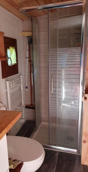 Un baño con cabina de ducha de vidrio, inodoro y tocador de madera.