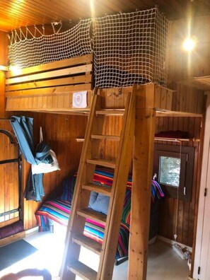 Un interior de madera con una litera, una escalera y un ventanal.