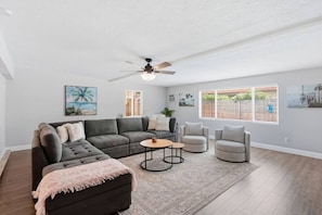 A living room with a sectional sofa, two armchairs, a coffee table, and a ceiling fan. - Boynton Beach Escape | Private Pool + 3BR (Boynton Beach)
