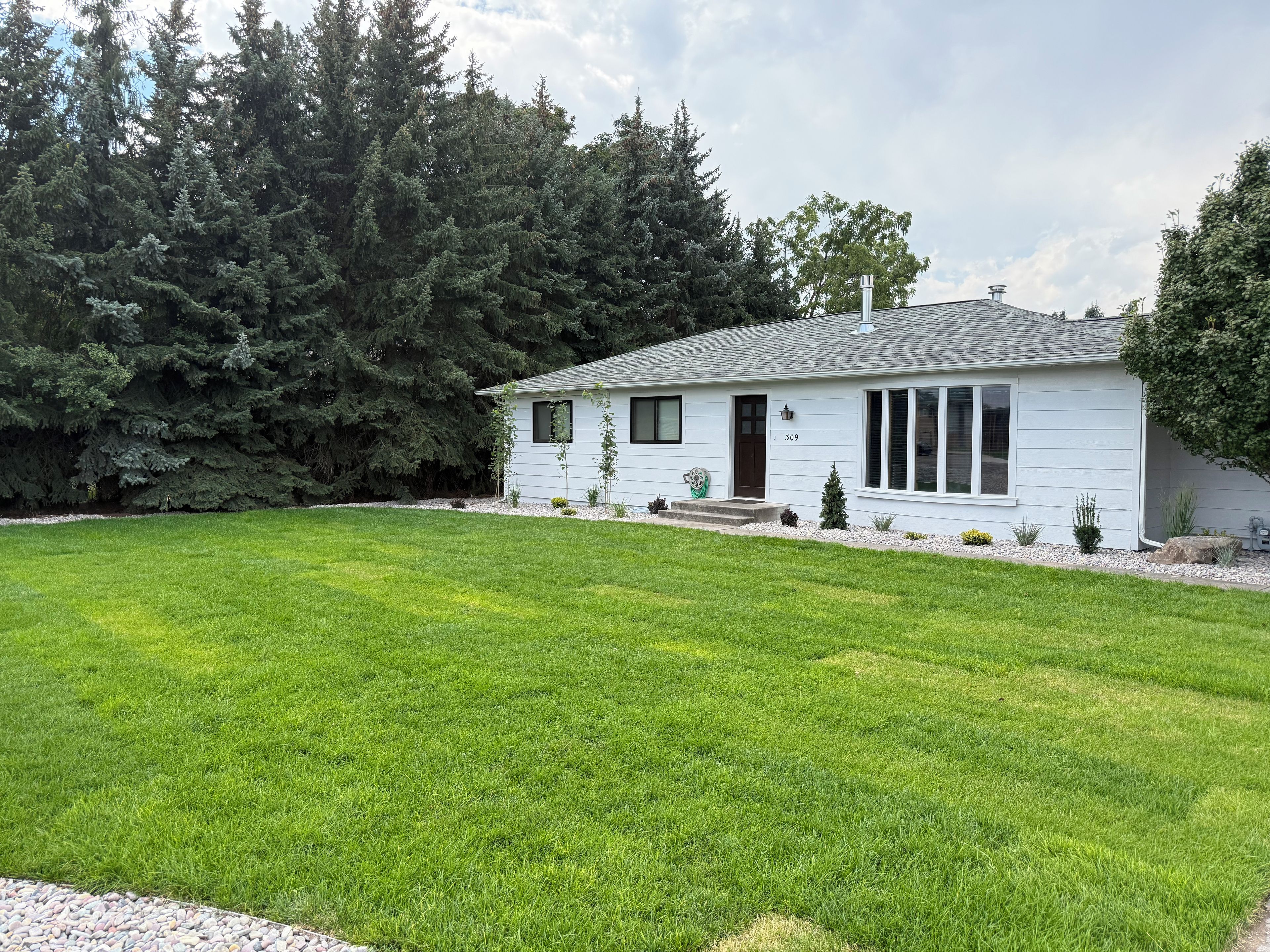 A single-story house with a well-maintained lawn and a small garden area.