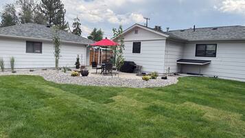 A residential property with a patio area, a barbecue grill, and a covered seating area.