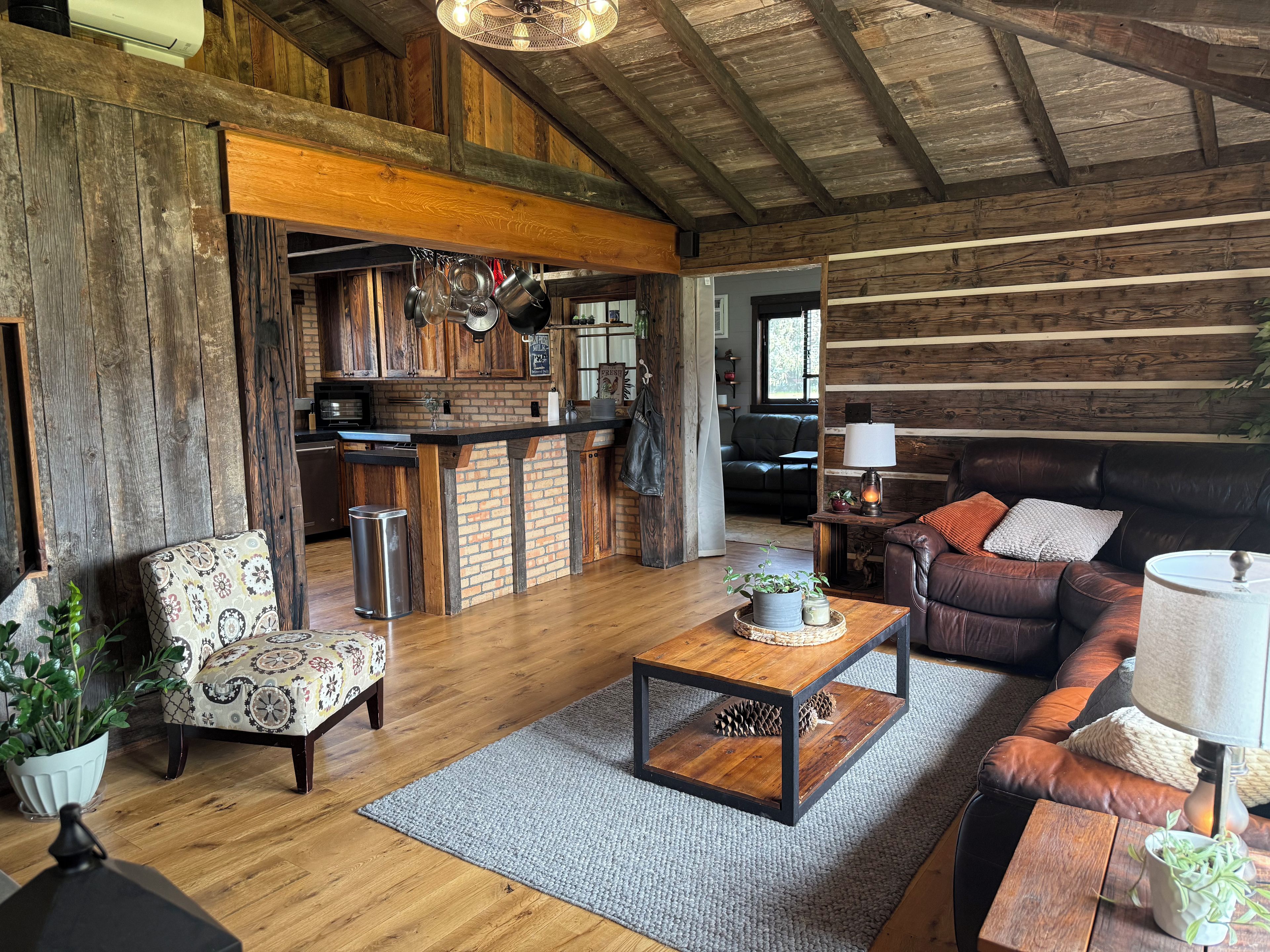 Un intérieur rustique avec un plafond en bois, un coin cuisine, un canapé en cuir et une table à manger.