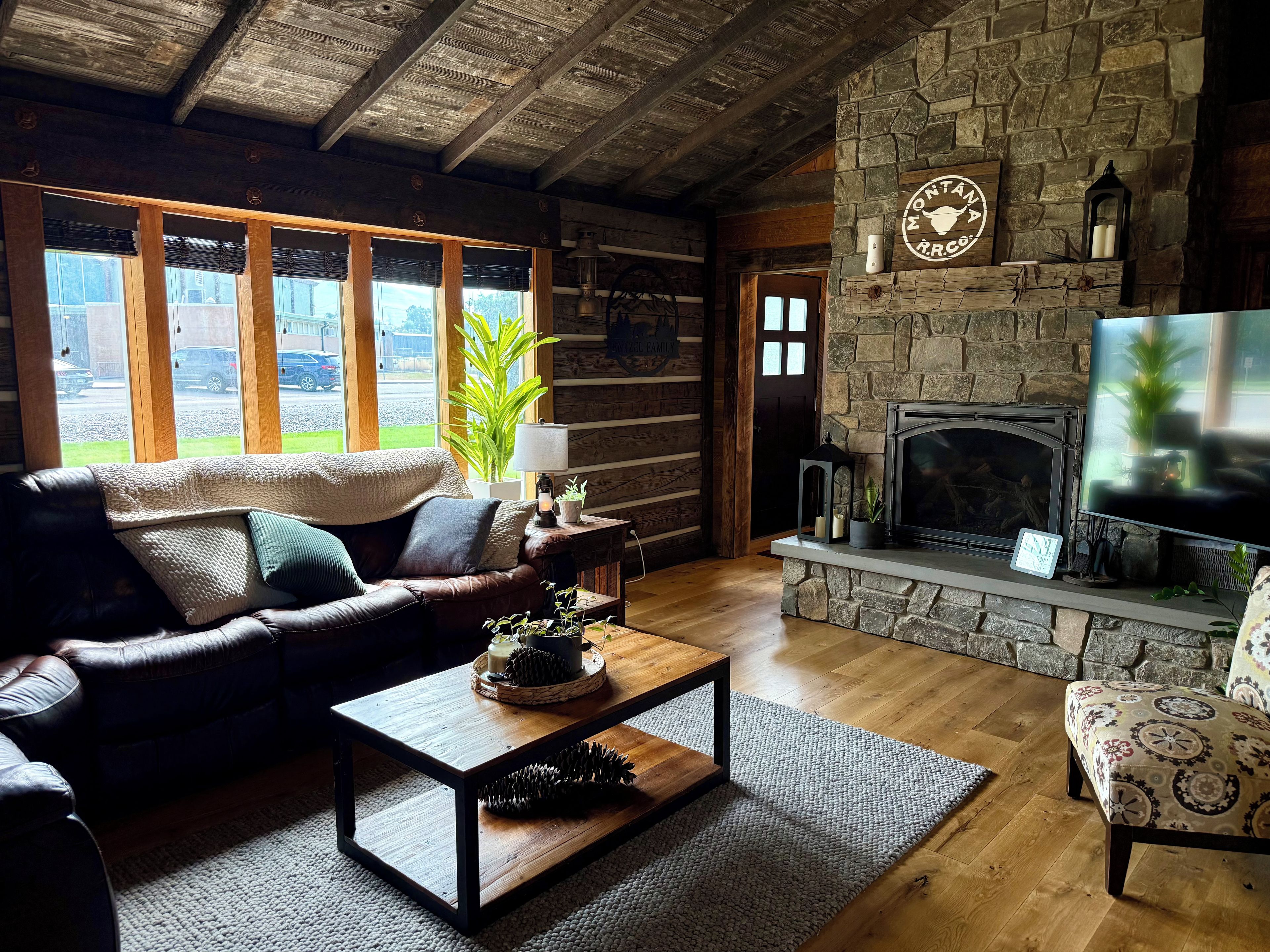 A cozy living room with a stone fireplace, leather sofa, and a television.