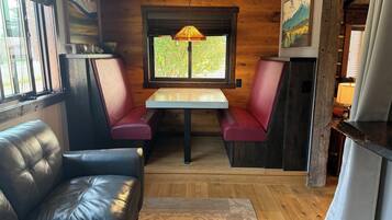 A cozy interior with a leather couch, wooden walls, a table with benches, and artwork.