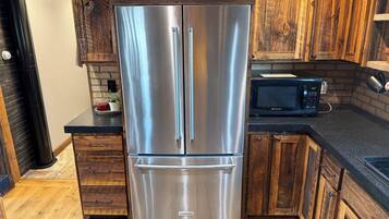 A kitchen with a stainless steel refrigerator, wooden cabinets, a microwave, and a countertop.