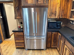 A kitchen with a stainless steel refrigerator, wooden cabinets, a microwave, and a countertop.