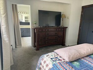 A bedroom with a bed, a dresser, a television, and a door.