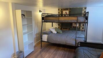 A bunk bed with a lower bunk, a bedside table, and a wall-mounted shelf unit.