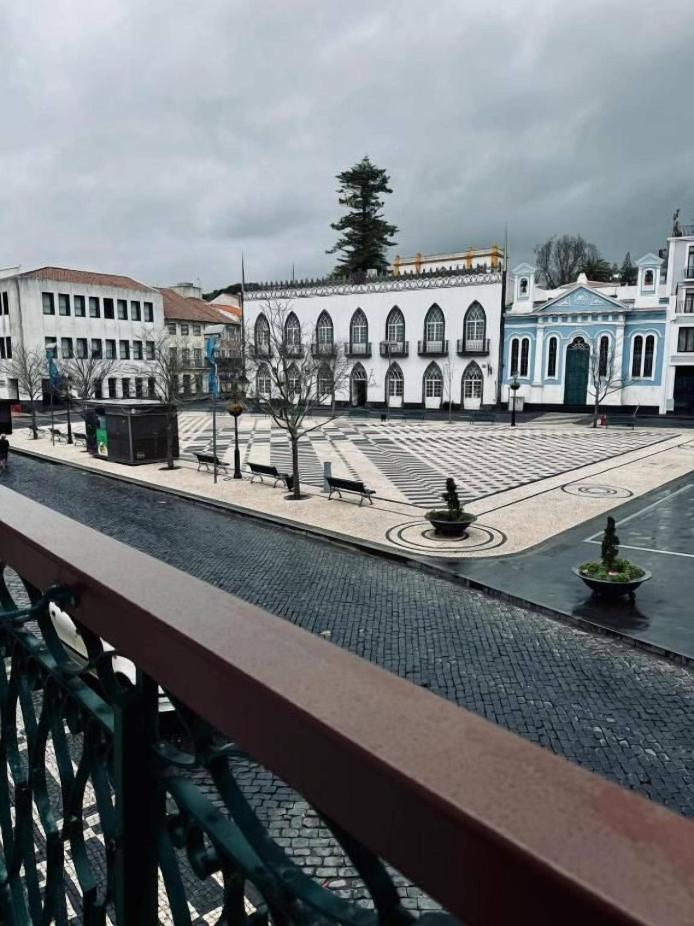 Un patio con una fuente, bancos y suelo de baldosas.