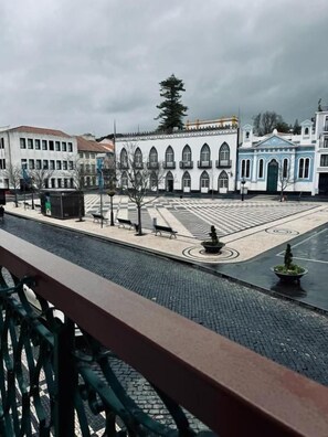 A courtyard with a fountain, benches, and a tiled floor.