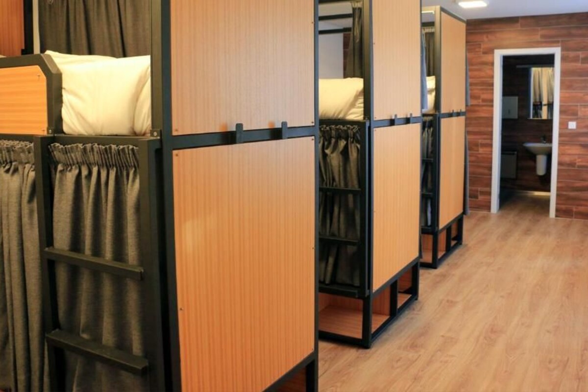 A hotel room with bunk beds, a wooden floor, and a bathroom visible through an open door.