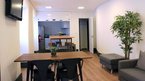 A modern living space with a dining area, a sofa, and a potted plant. - Aliança Café & Hostel  (Angra do Heroísmo)