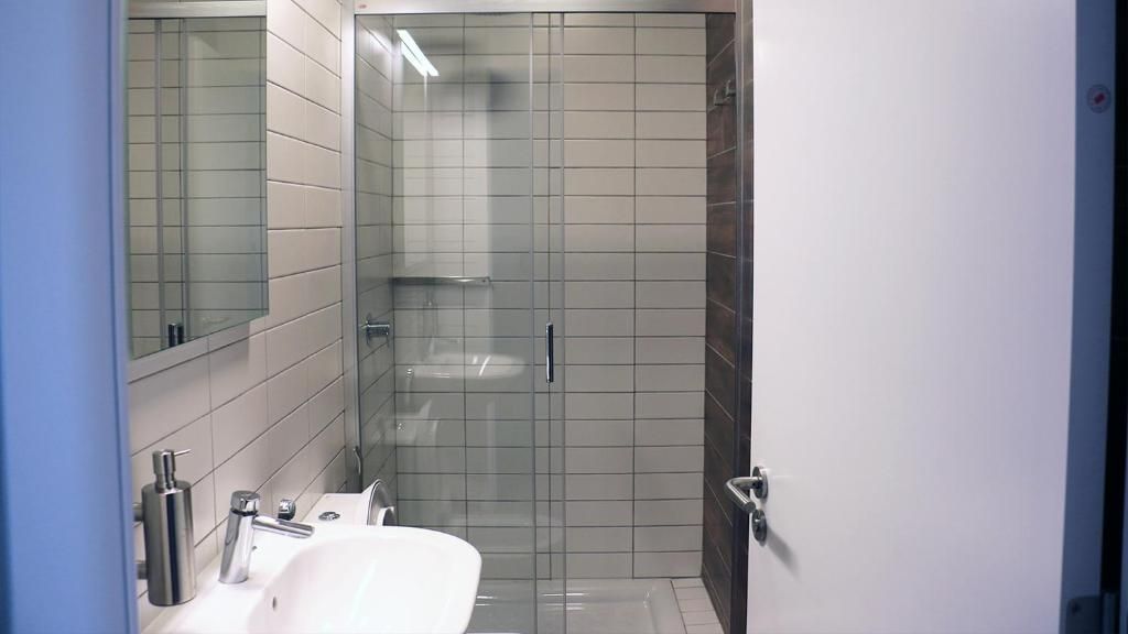 A bathroom with a glass-enclosed shower, a white sink, and a mirror.