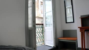 Ein Zimmer mit einer Schiebetür und einem Balkon, einer Holzbank und einem kleinen Tisch.