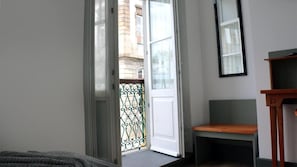 A room with a sliding glass door leading to a balcony, a wooden bench, and a small table.