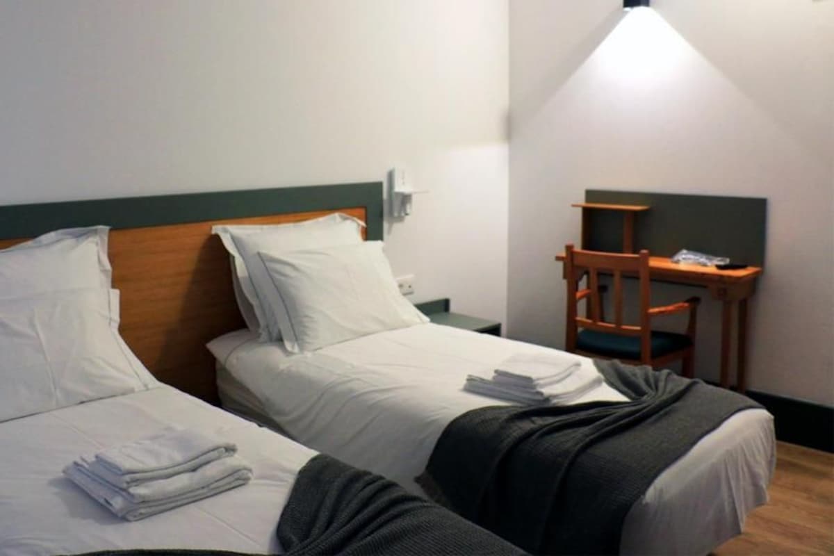 A hotel room with two beds, a desk, and a chair.