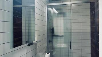 Casa de banho moderna com lavatório branco, sanita e cabine de duche com vidro.