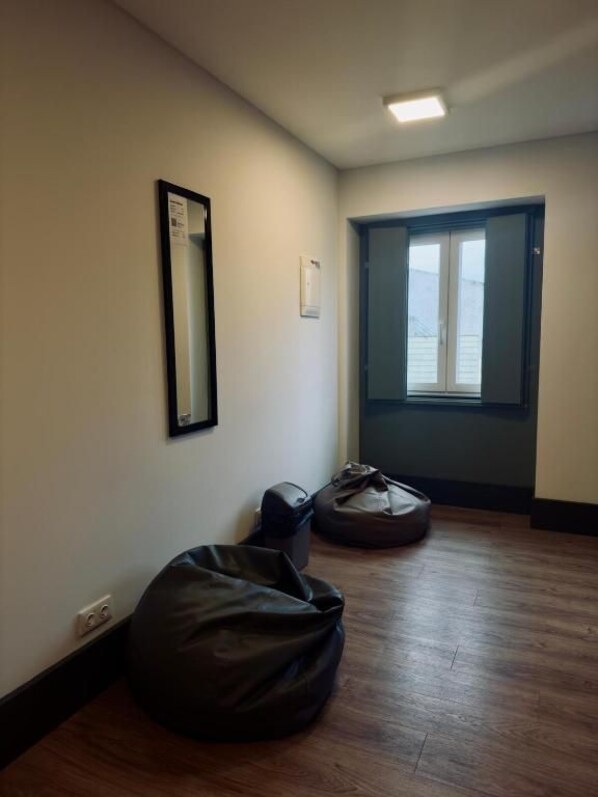 A room with a wooden floor, a mirror on the wall, a door with a view, and a bag on the floor.