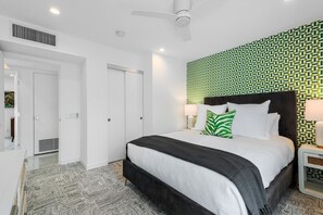 Ein Hotelzimmer mit einem Bett, einem Nachttisch, einer Wand mit geometrischem Muster und einem Deckenventilator.