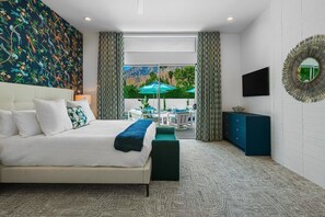 Ein modernes Schlafzimmer mit einem großen Bett, Blick ins Freie und einer Essecke mit Sonnenschirmen.