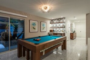 A pool table in a well-lit room with a glass door leading to an outdoor area. - Indian Canyons Bauhaus Estate (Palm Springs)