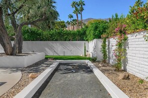 A landscaped garden with a rectangular water feature, a tree, and a white wall with climbing plants. - Indian Canyons Bauhaus Estate (Palm Springs)