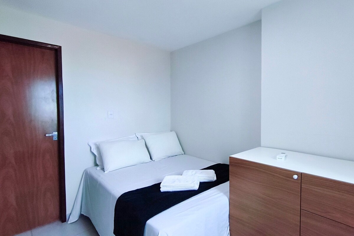 A bedroom with a bed, a wooden dresser, and a door.