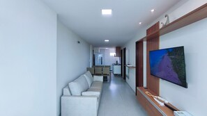 A modern interior with a sofa, dining area, and a TV on the wall. - Prive Paraiso Praia dos Carneiros (Tamandaré)