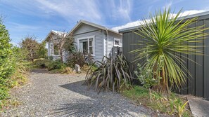 A residential property with a gravel driveway, a house with a sloped roof, and a variety of plants including a prominent palm-like plant.