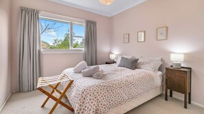 A bedroom with a bed, a nightstand, a lamp, and a window with curtains.