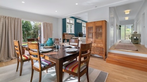 Un comedor con una mesa y sillas de madera, un televisor y vistas al exterior.