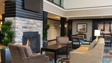 A modern lobby with a stone fireplace, comfortable seating, and a dining area.