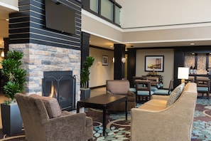 A modern lobby with a stone fireplace, comfortable seating, and a dining area. - Accessible 1BR Suite w/ Kitchen & Hot Breakfast (Oakbrook Terrace)