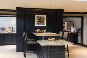A modern kitchen with dark cabinetry, a granite countertop, and a framed artwork above the island.
