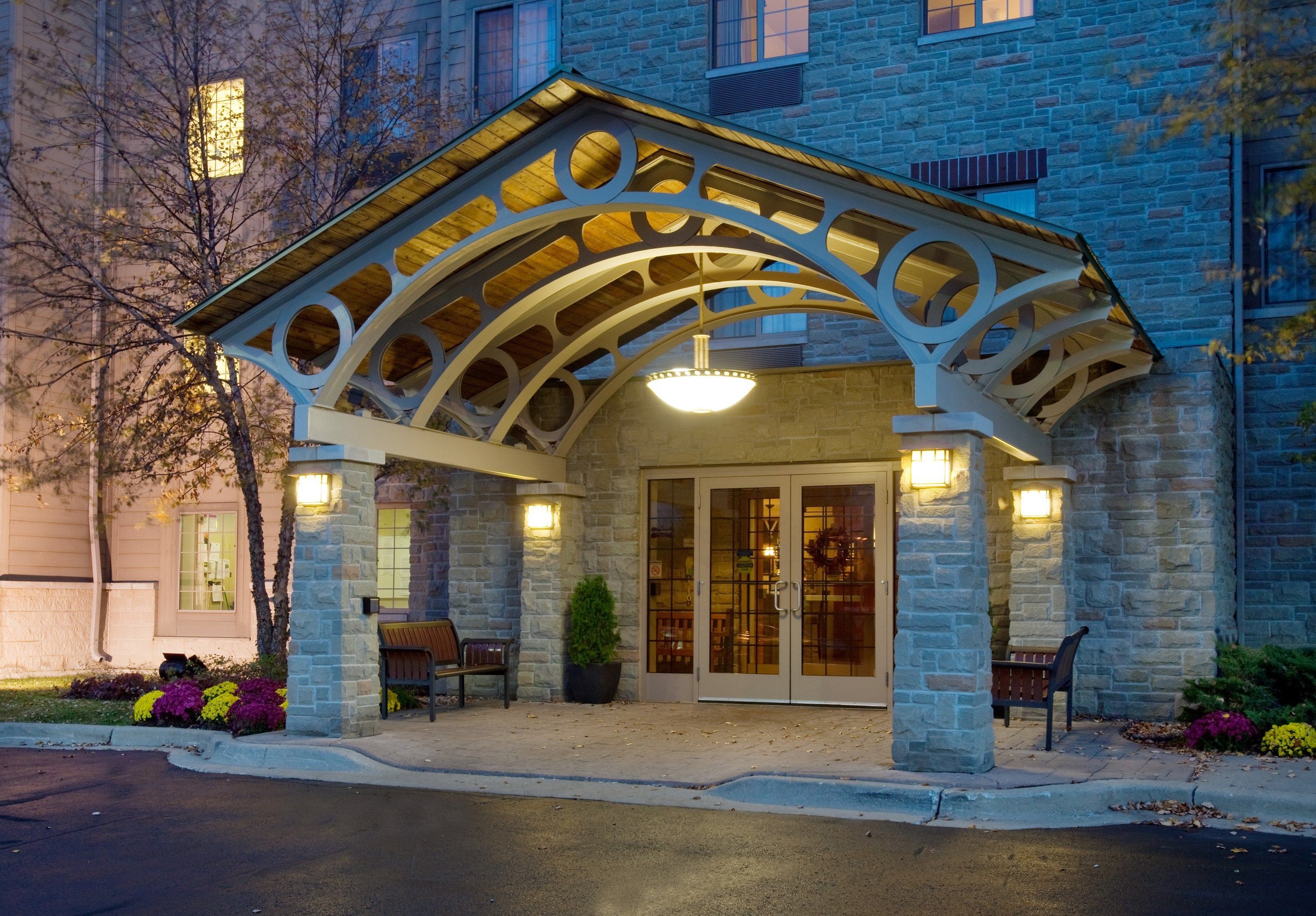 A stone building with a covered entrance, benches, and potted plants.