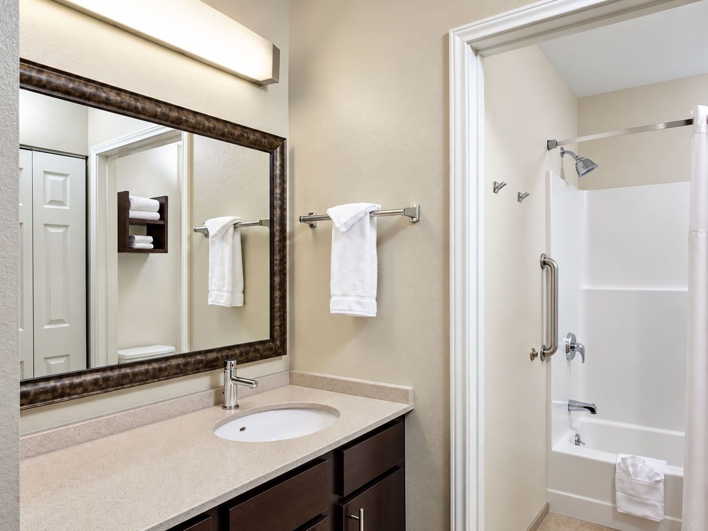 A bathroom with a sink, mirror, towel rack, and a shower area.