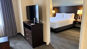 Een hotelkamer met een bed, bedlampen, een televisie op een dressoir en een gordijn.