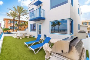 Eine moderne Terrassenanlage im Freien mit Grill, Lounge-Möbeln und Blick auf den Strand.
