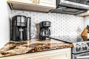 A kitchen with a coffee maker, a stove, and a patterned backsplash. - Between Sand & Sea Beach Home (Hollywood)