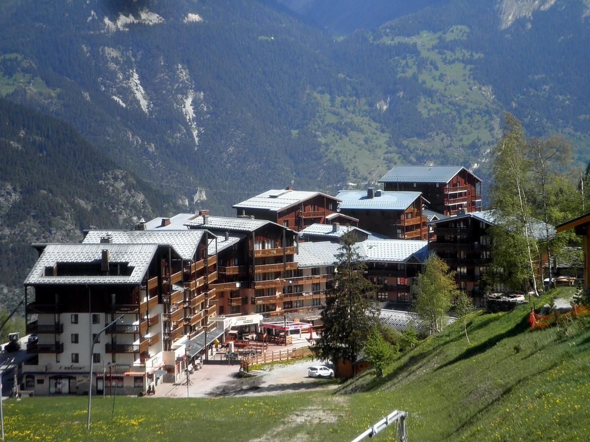 A mountain lodge with multiple buildings, a ski lift, and a clear view of the surrounding mountains.