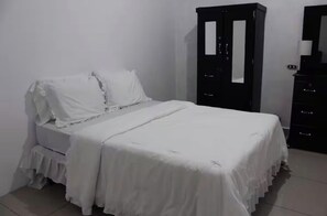 Un dormitorio con una cama, un armario y un aparador.