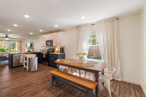 Cozinha moderna com área de refeições, piso de madeira e vista para o exterior.