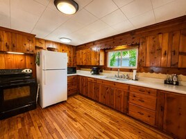 Una cocina con armarios de madera, un refrigerador, una estufa, un microondas y un lavaplatos.