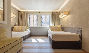 A hotel room with two beds, a sofa, a window with curtains, and a patterned wall. - BEAUTIFUL 3-BEDROOM DORSODURO APARTMENT WITH PRIVATE GARDEN (Venezia)